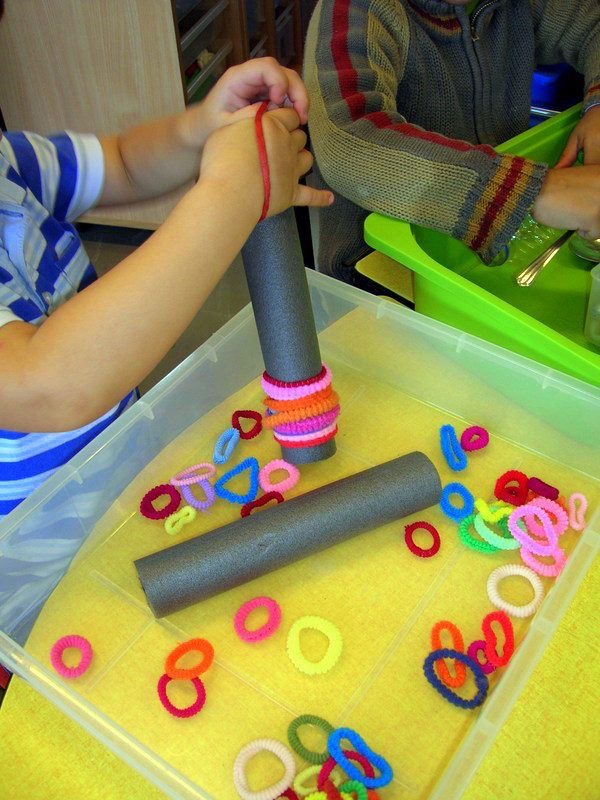 Des enfants manipulant des anneaux colorés et développant leur motricité fine à Atelier Soleil